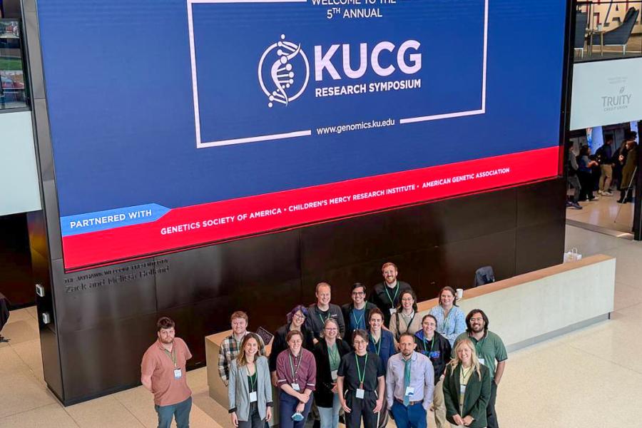 Group of attendees stand before a event sign