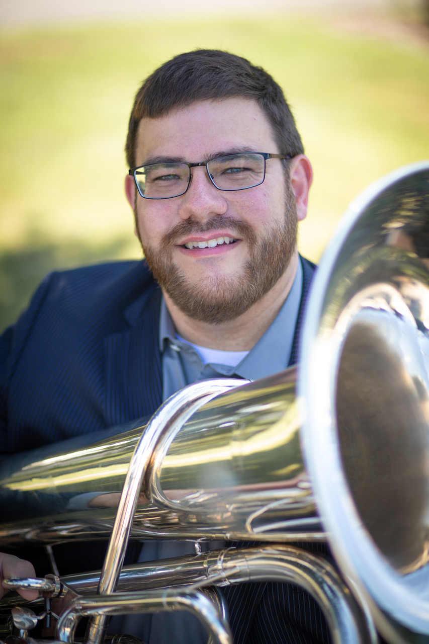 a man seated and holding a tuba