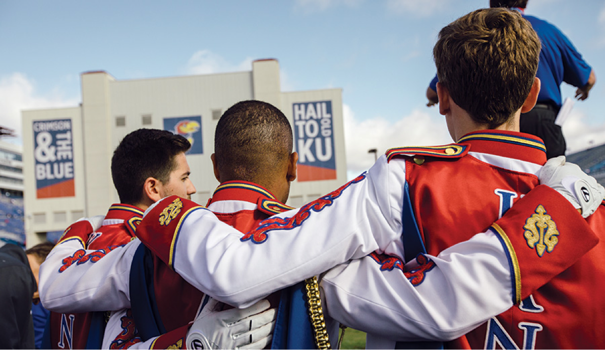 KU marching band members stand with their arms around each other