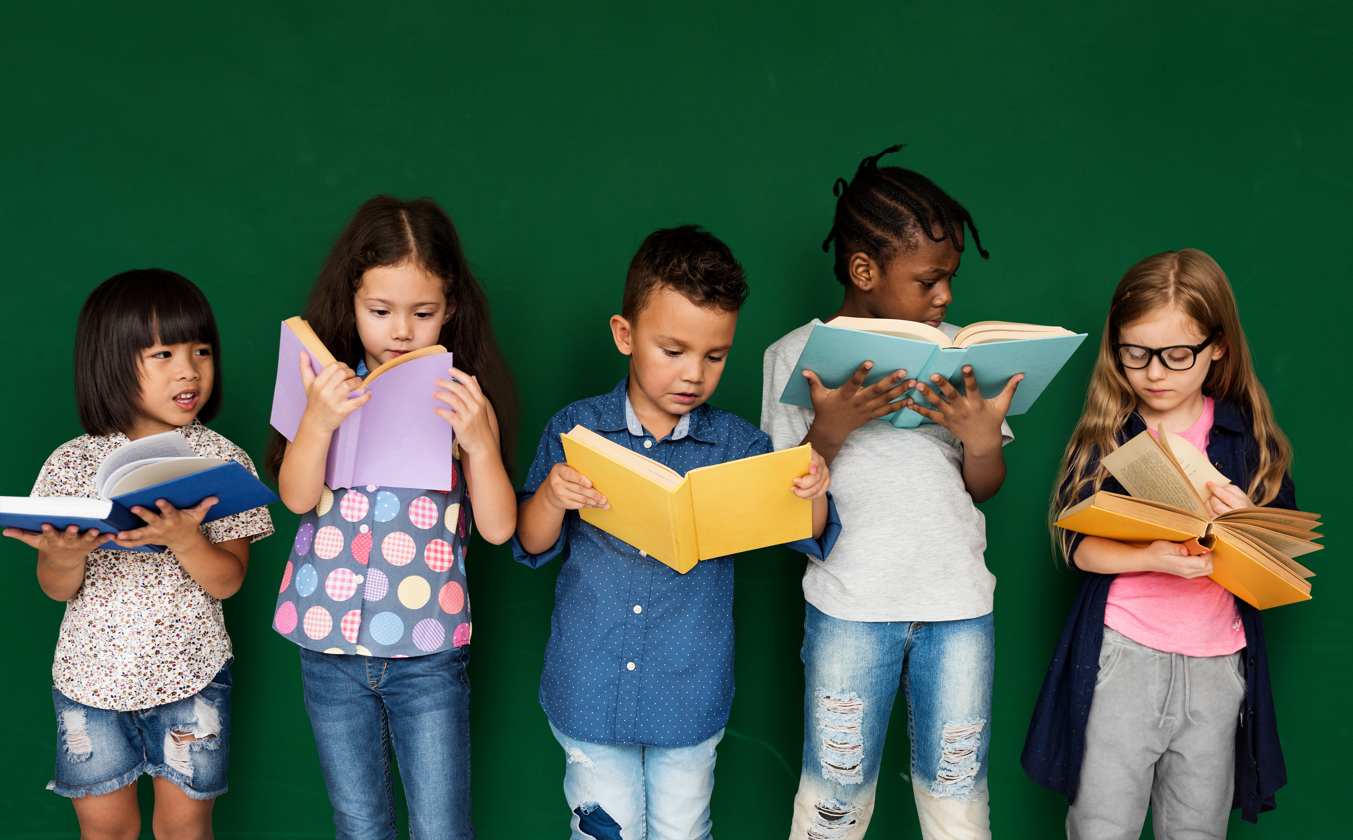 "Five elementary school aged boys and girls stand and reads books"