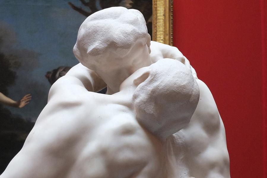 A closeup photo of Auguste Rodin's sculpture The Kiss in an art museum.
