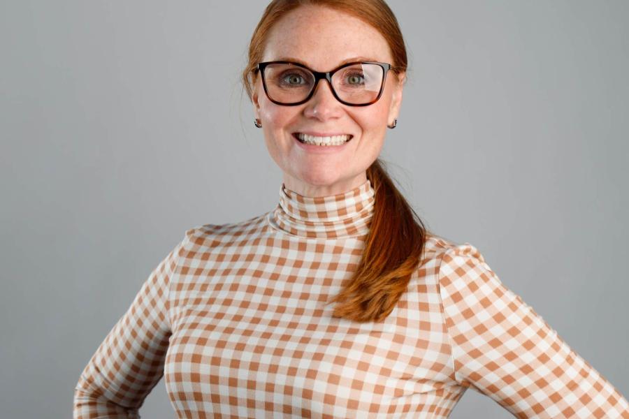 A photo of Kari Murphy wearing glasses, a checkered shirt, and small hoop earrings.