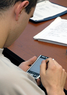 A KU student reviews his team's work on a PDA