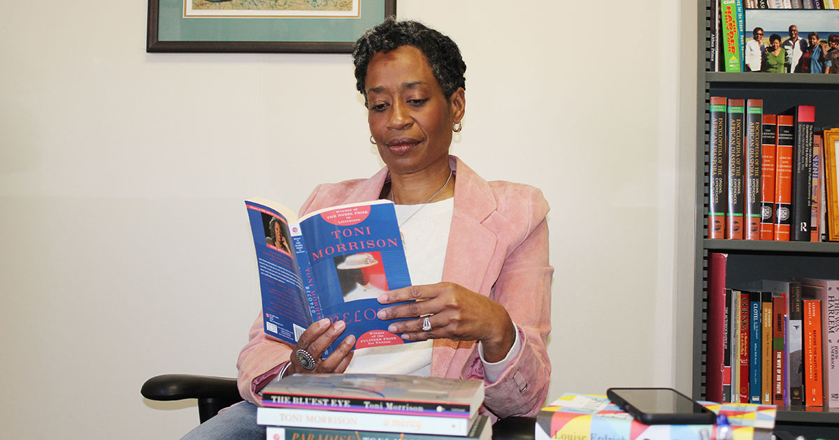 Giselle Anatol reads from her collection of Toni Morrison books in her Wescoe Hall office. Credit: Rick Hellman, KU News Service.