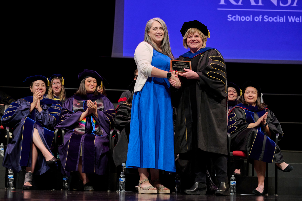 Audrey Cress receives Adjunct Teaching award from Dean Michelle Carney on stage at graduation.