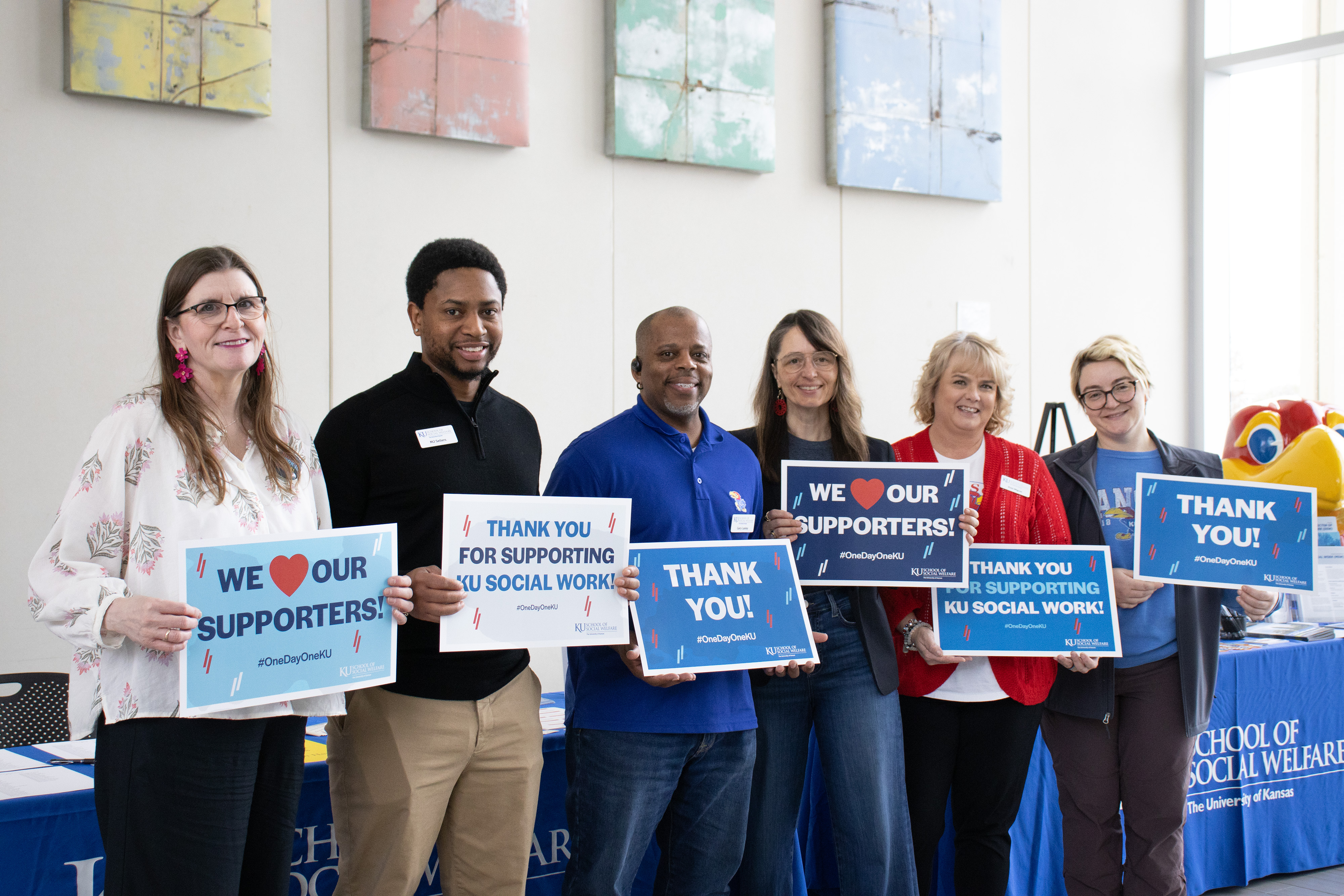 Practicum Education Office and student support staff hold "thank you" signs for One Day One KU.