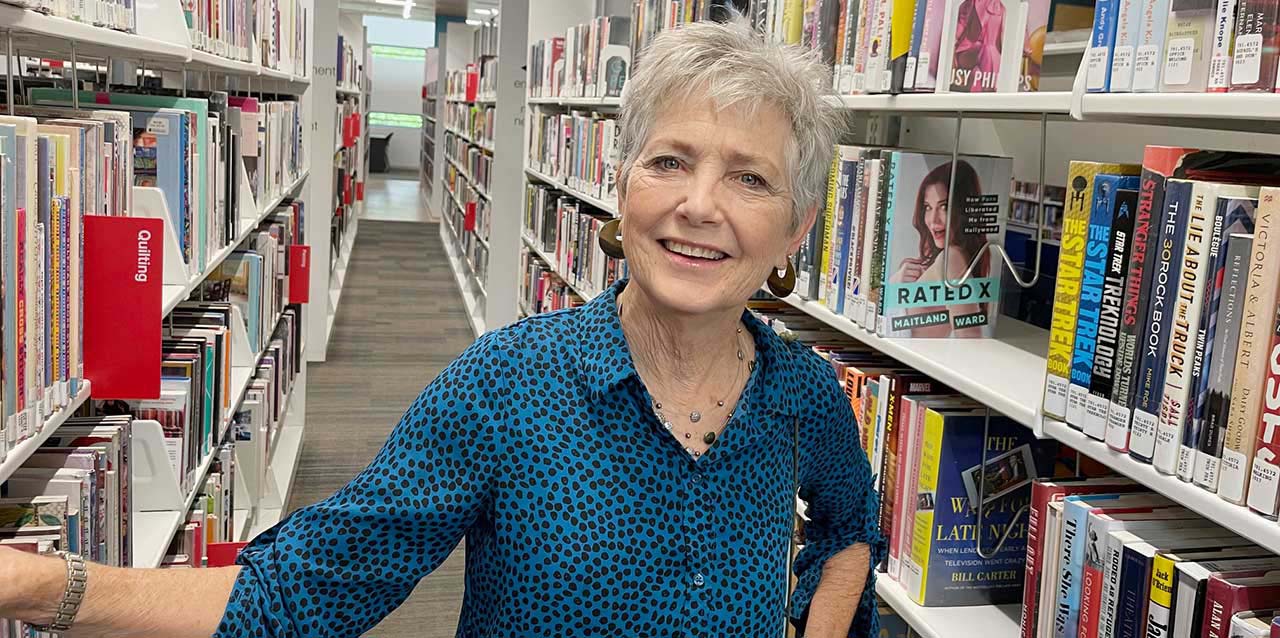 Liz Langdon, standing among library shelves