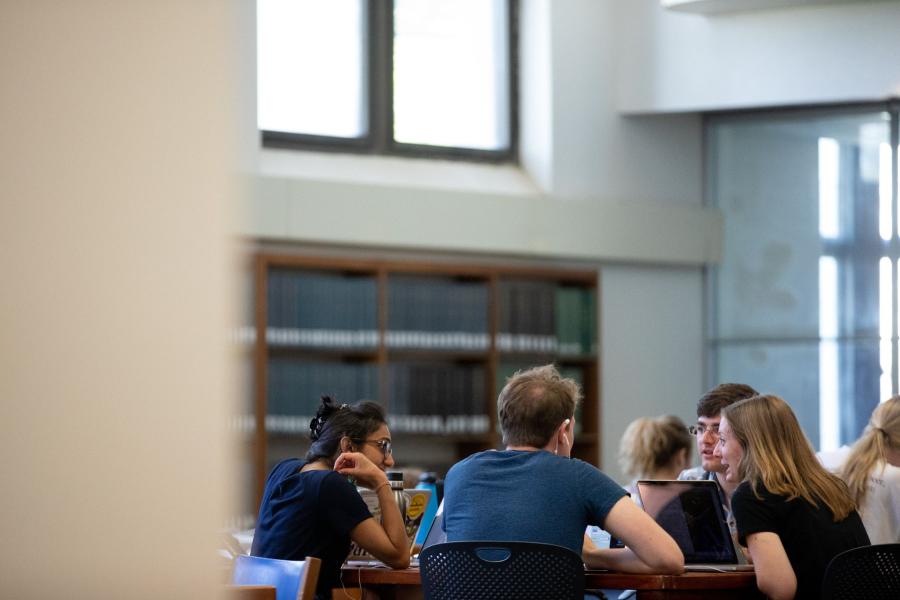 Students study at a group study table inside Watson Library.