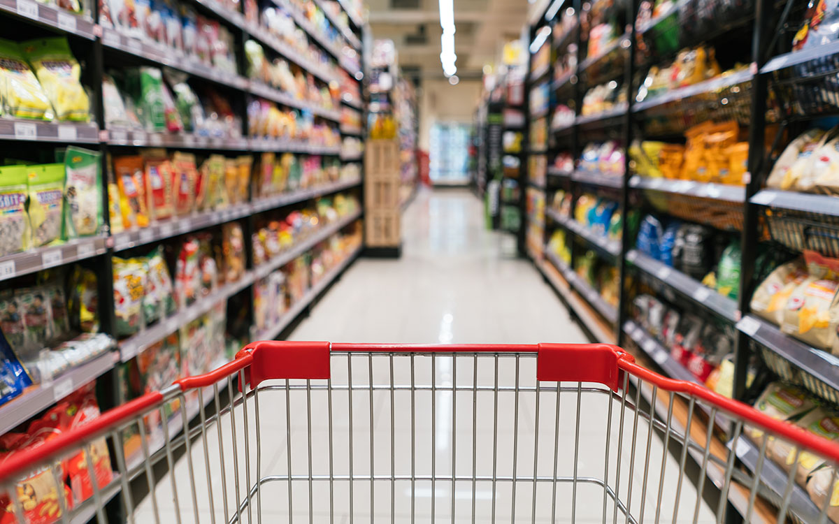 A grocery cart between the aisles of a supermarket.