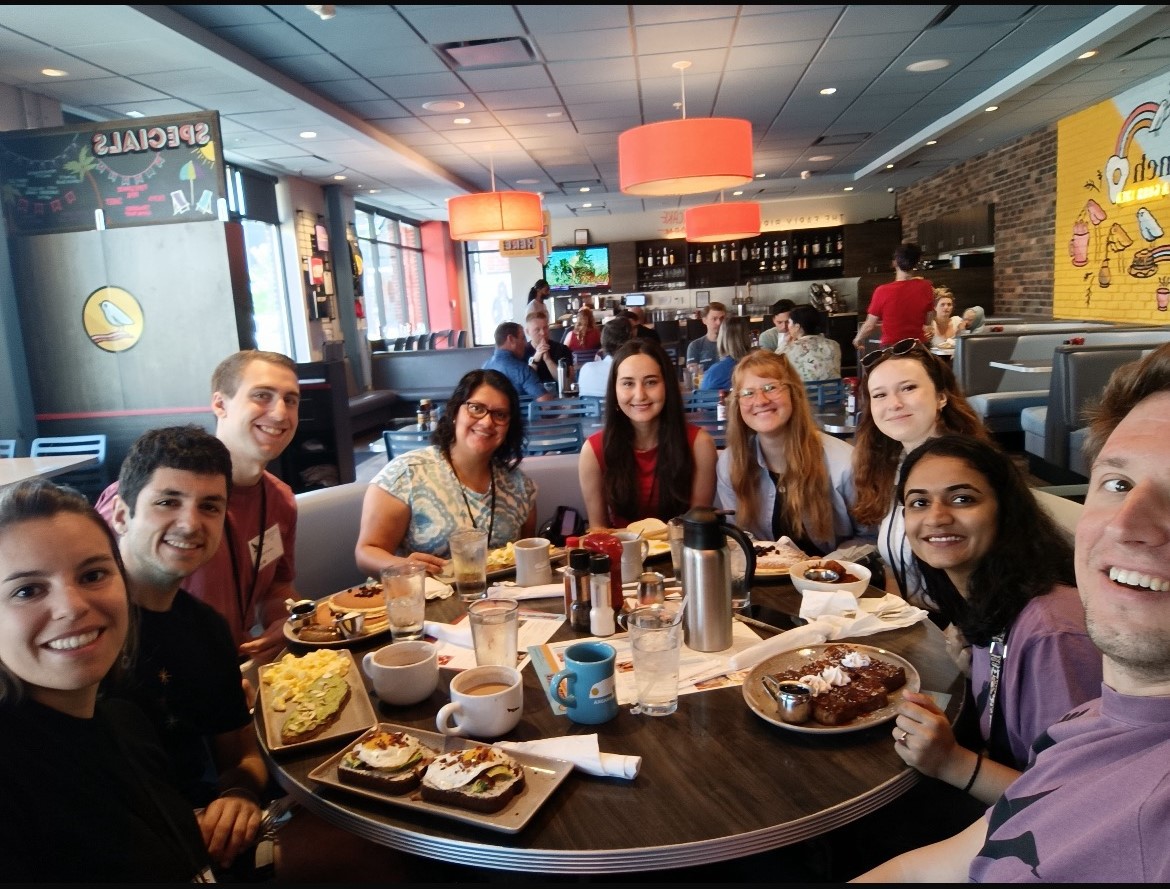 Kiana Hajiarbabi with other conference attendees sitting around a dining table.
