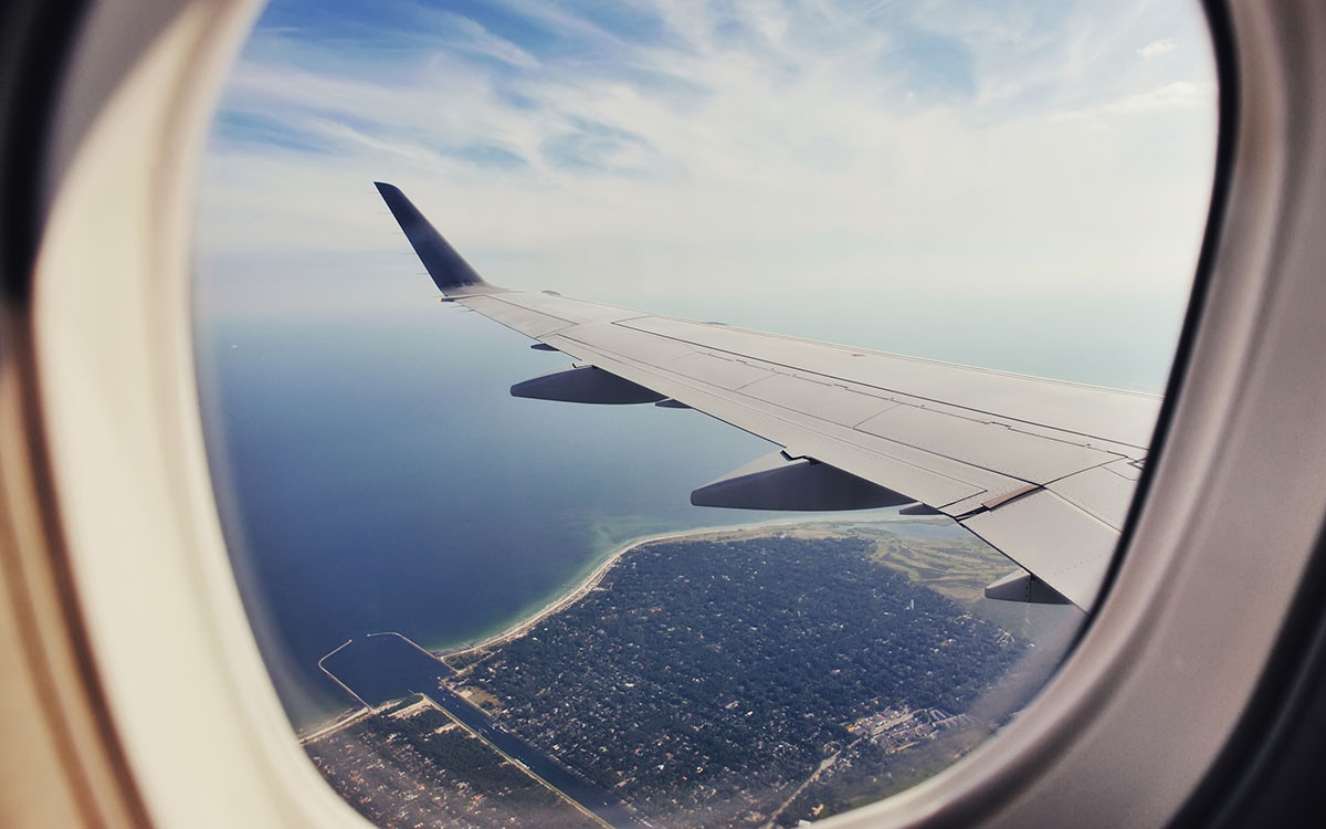 View out a plane window showing residential coastline, water.