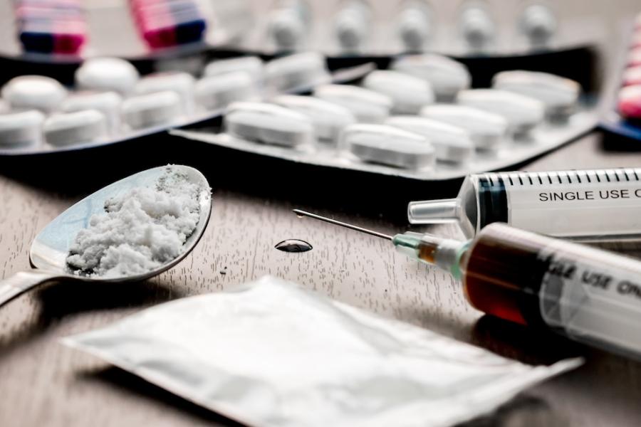 Illegal drugs and drug paraphernalia of many types litter a table.