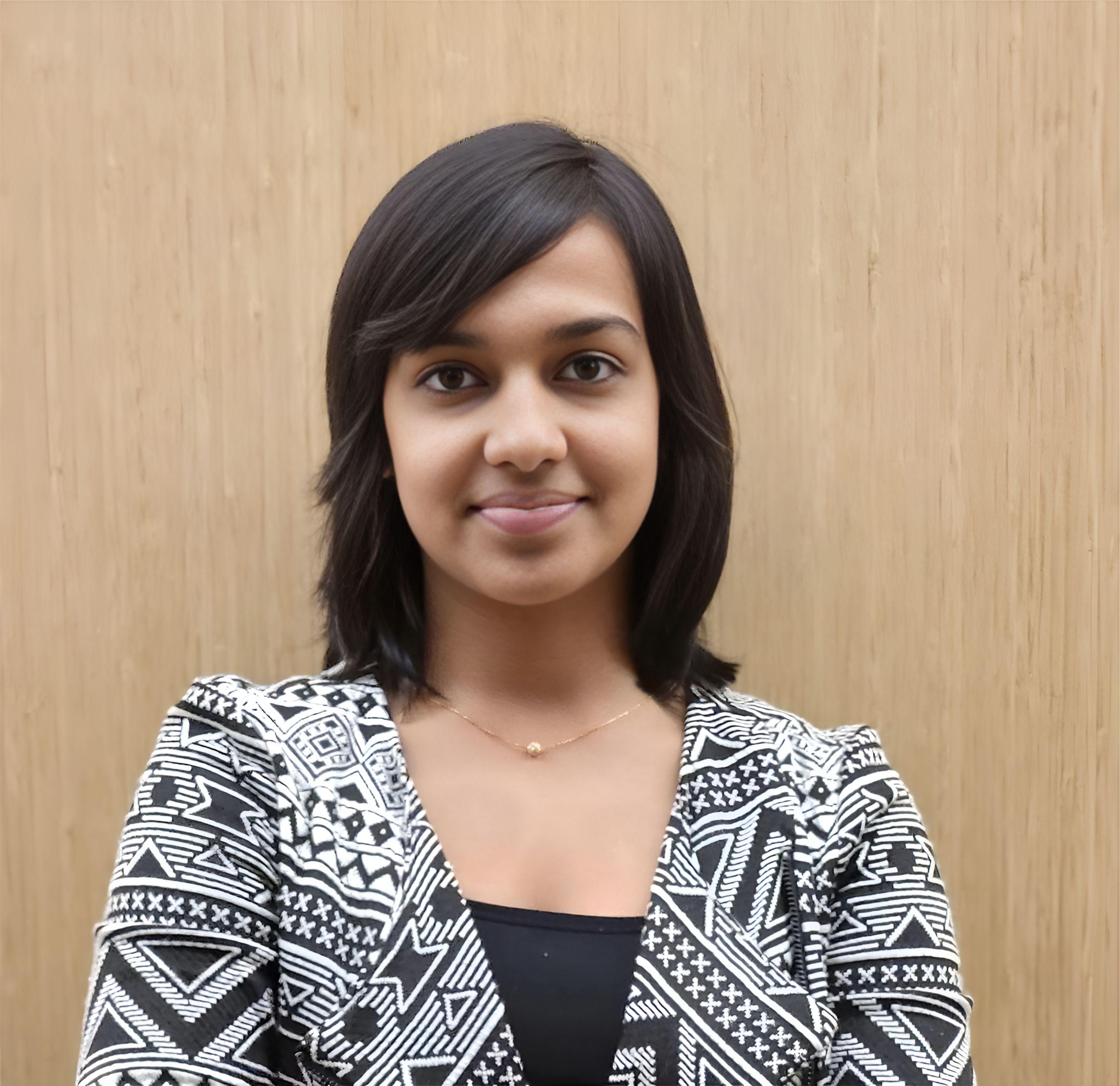 Pragati Maheshwary looking at the camera ans wearing a black shirt with a black and white jacket.