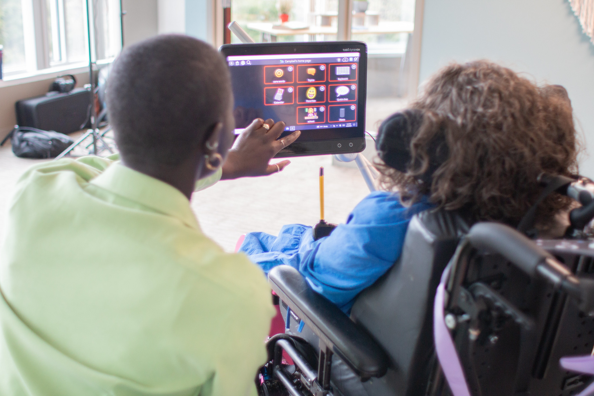 "Two women sit next to each other and communicate with the help of an AAC device"