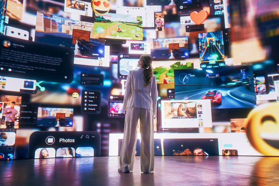A photo of a woman from behind standing before a massive wall representing various websites, online and entertainment options including emojis and numerous online options.