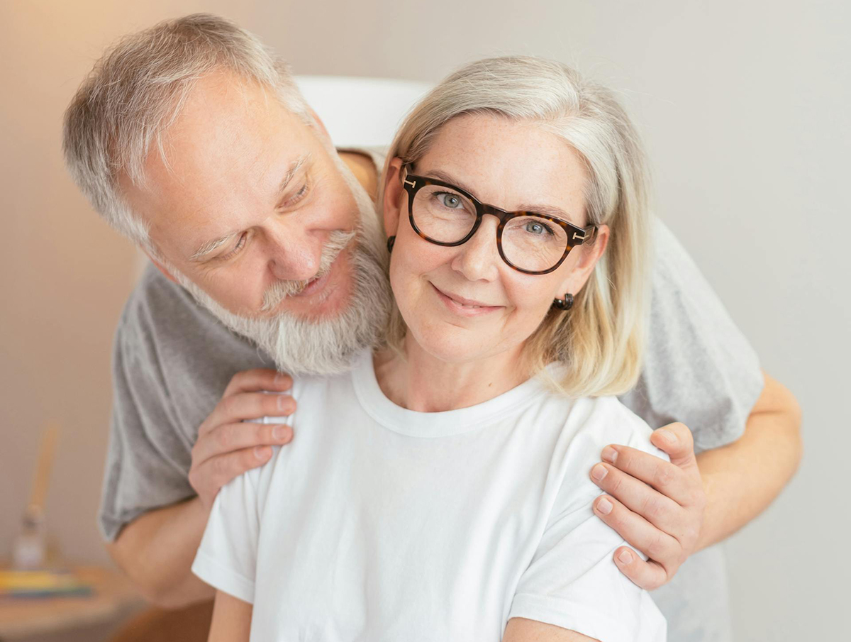 "A man and woman with gray hair smile while posing together"