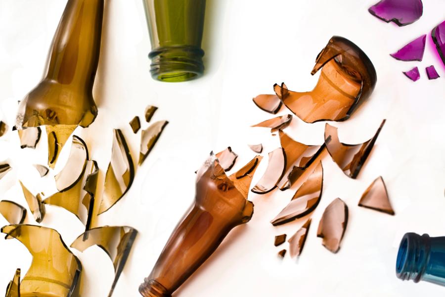 Broken bottles of varying colors against a white background.