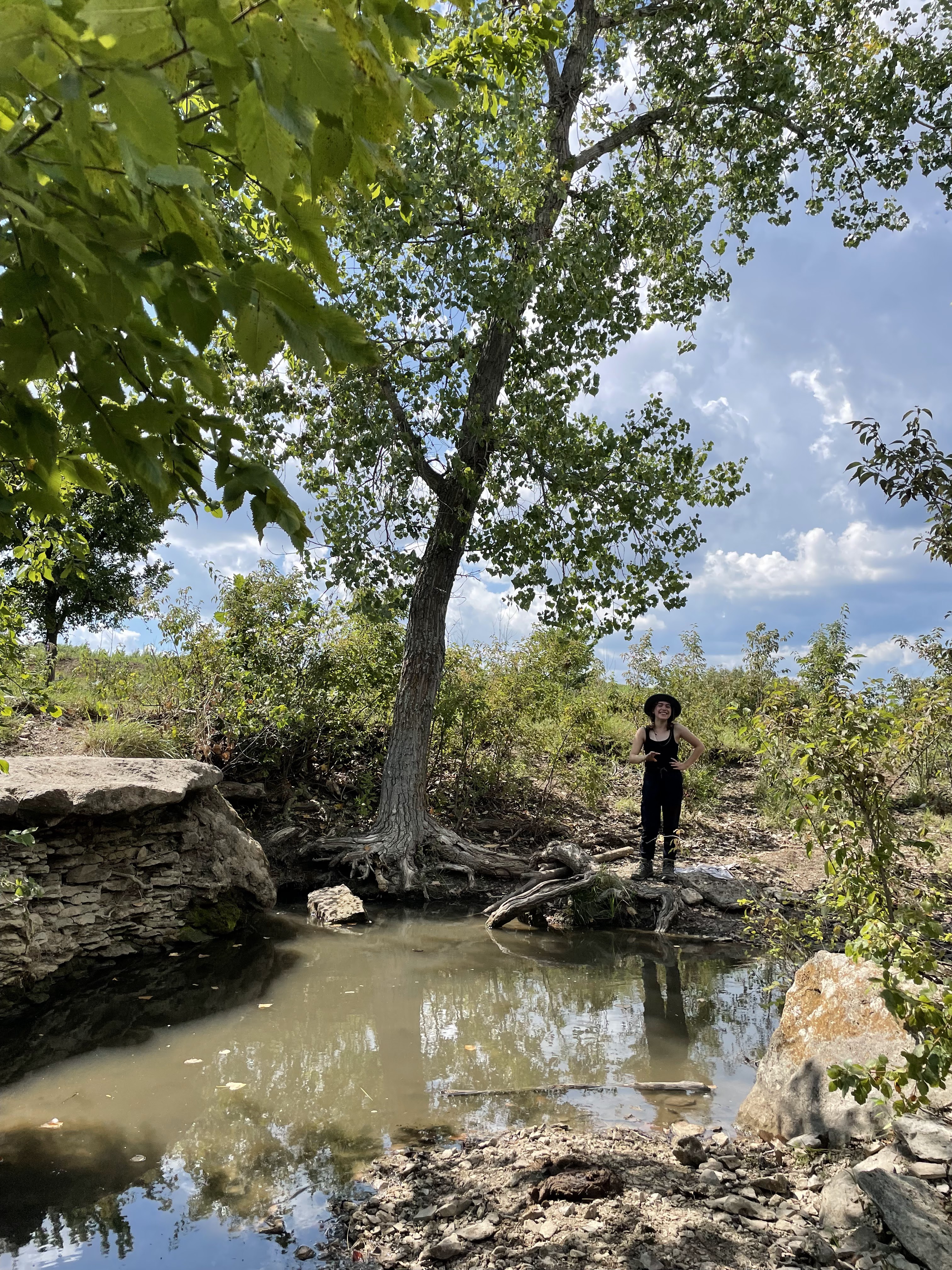 Eva standing by pond near a large tree