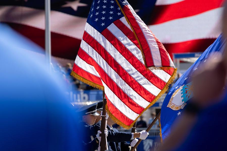 KU ROTC members carry American flag at sporting event.