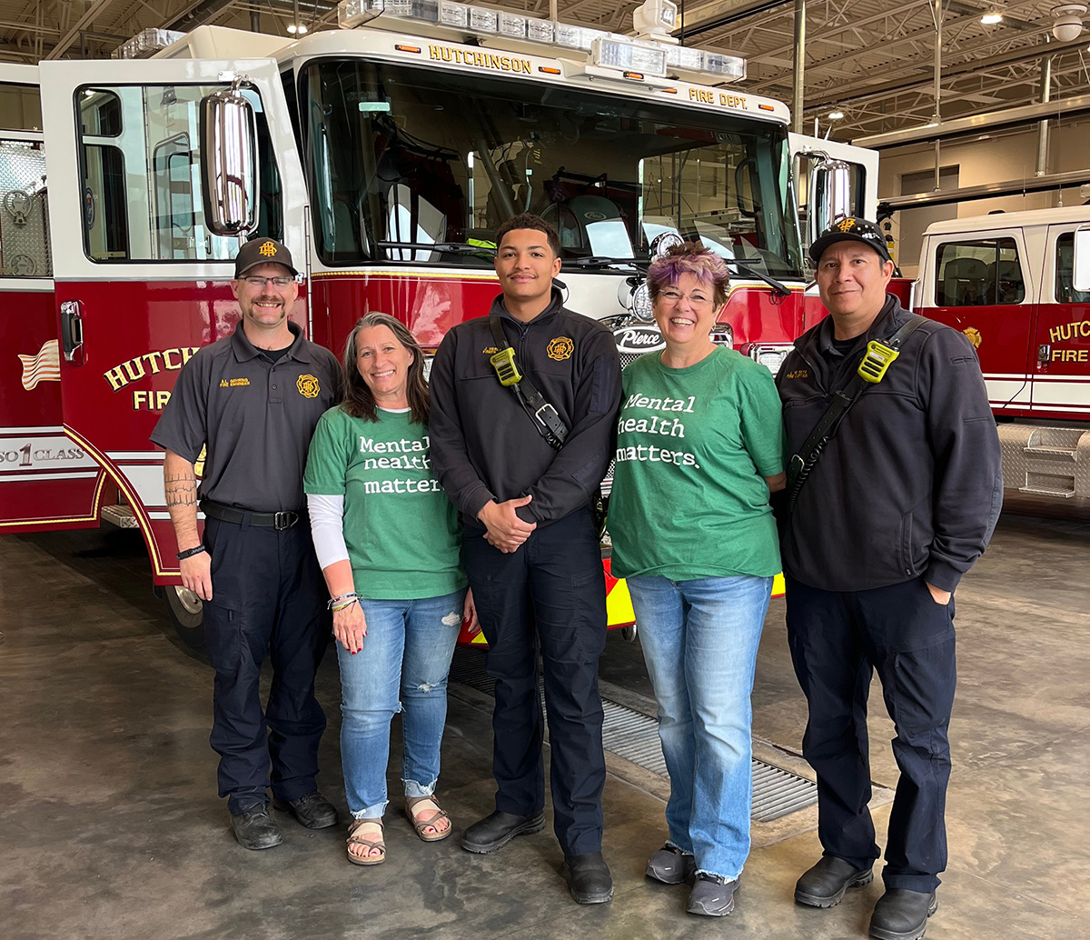 Beth Akins and Pat Willis standing with three first responders in front of a fire truck. 