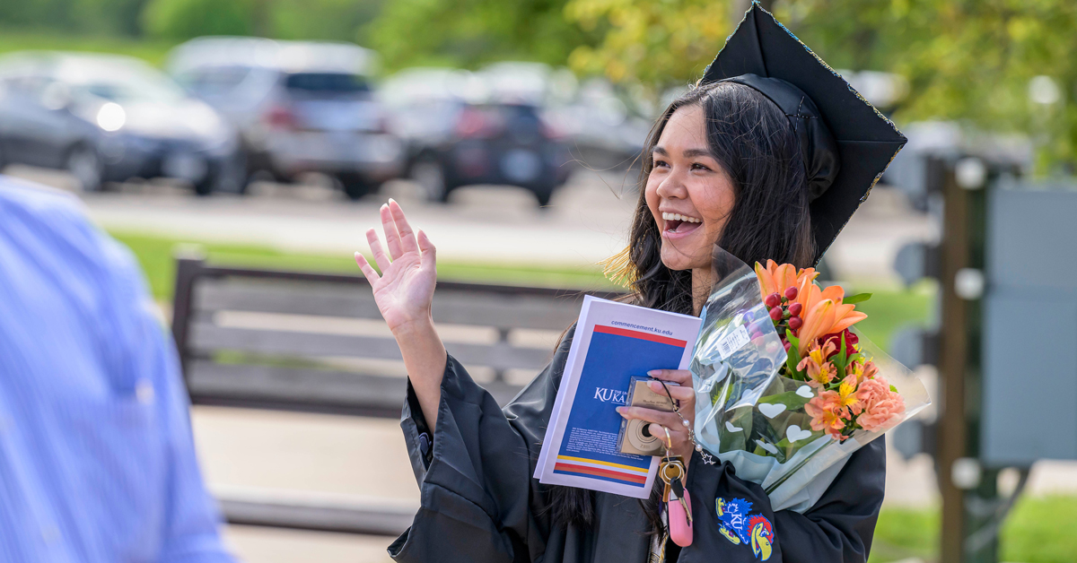 Olivia Sourivong waves to family and friends at the KU School of Social Welfare graduation ceremony