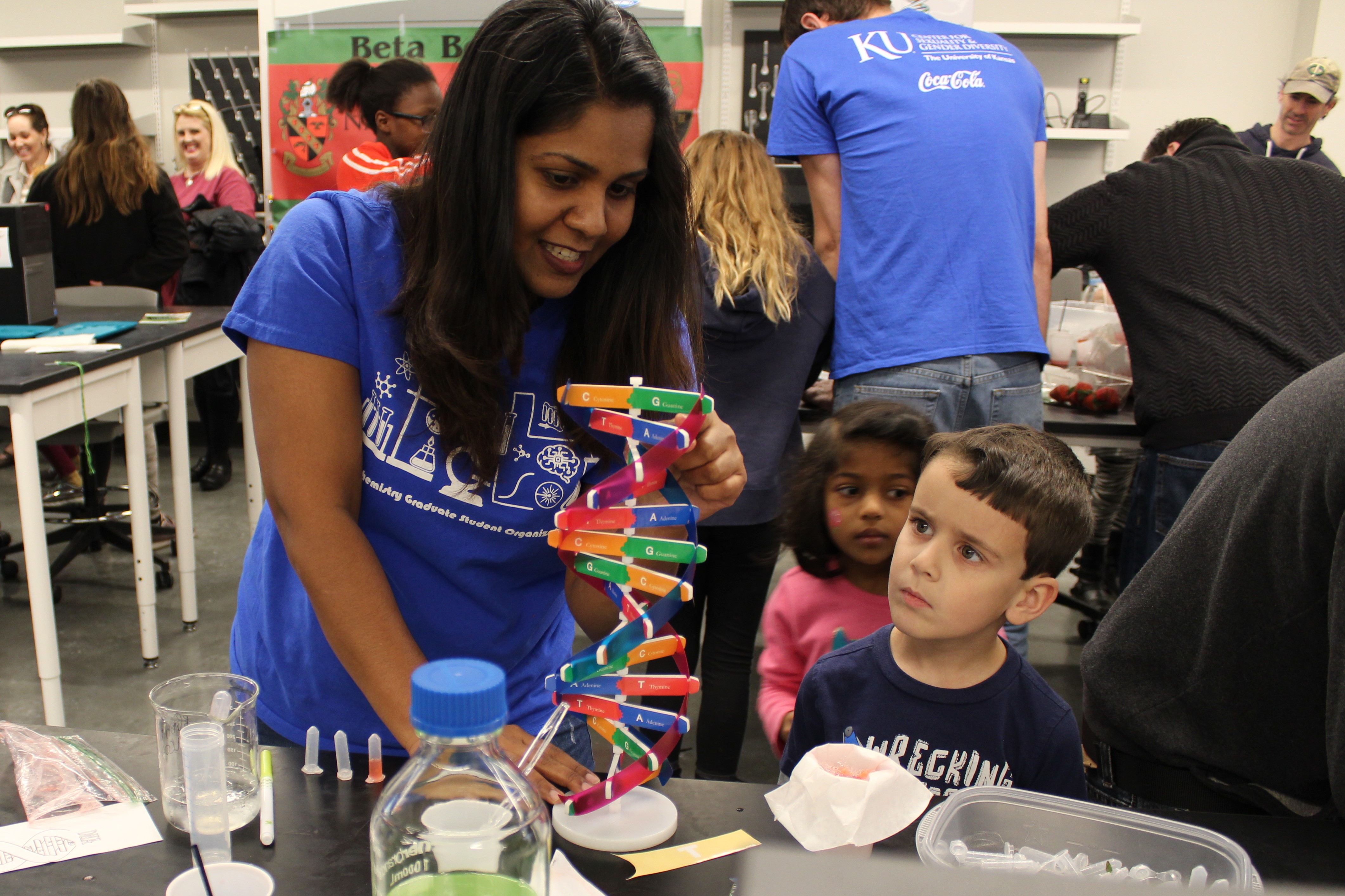 Helper in blue shirt assisting a child with a structure.