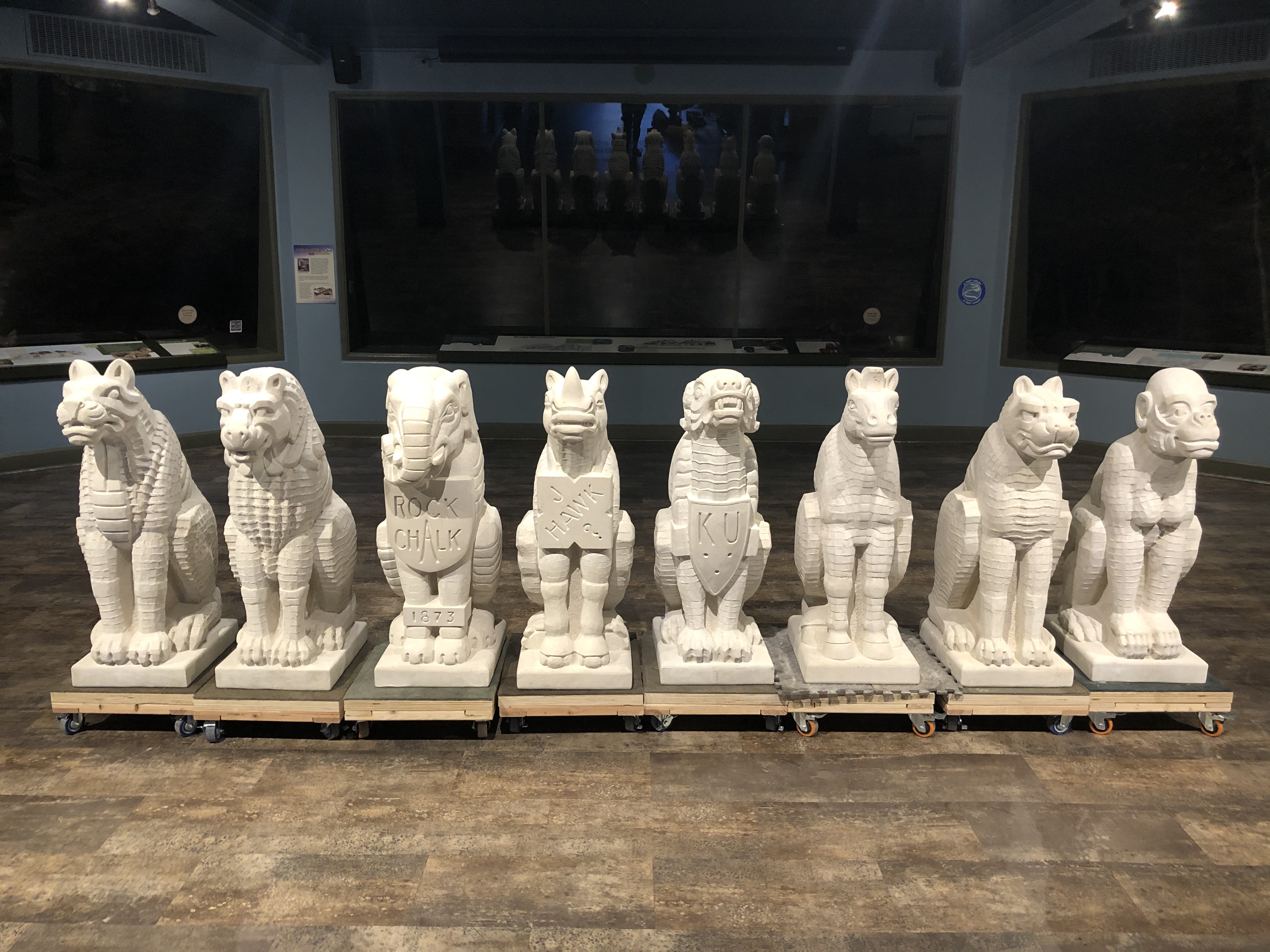 Eight limestone grotesques stand on display in the Panorama Gallery at the KU Natural History Museum. 