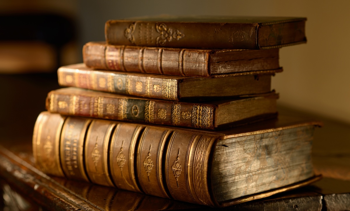 A stack of 17th century books sits upon an antique table.
