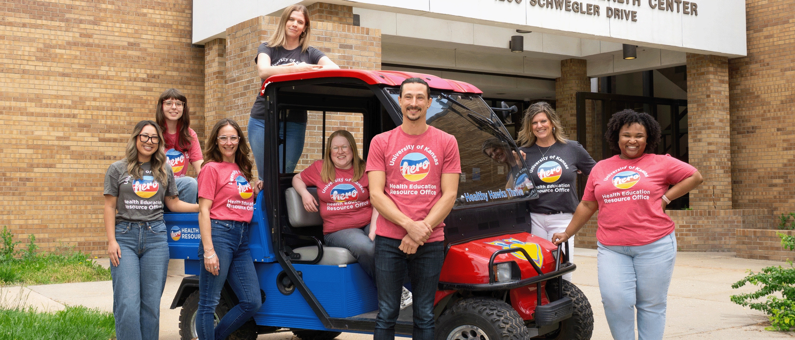HERO staff posing next to a golf cart in front of the Watkins Health Center