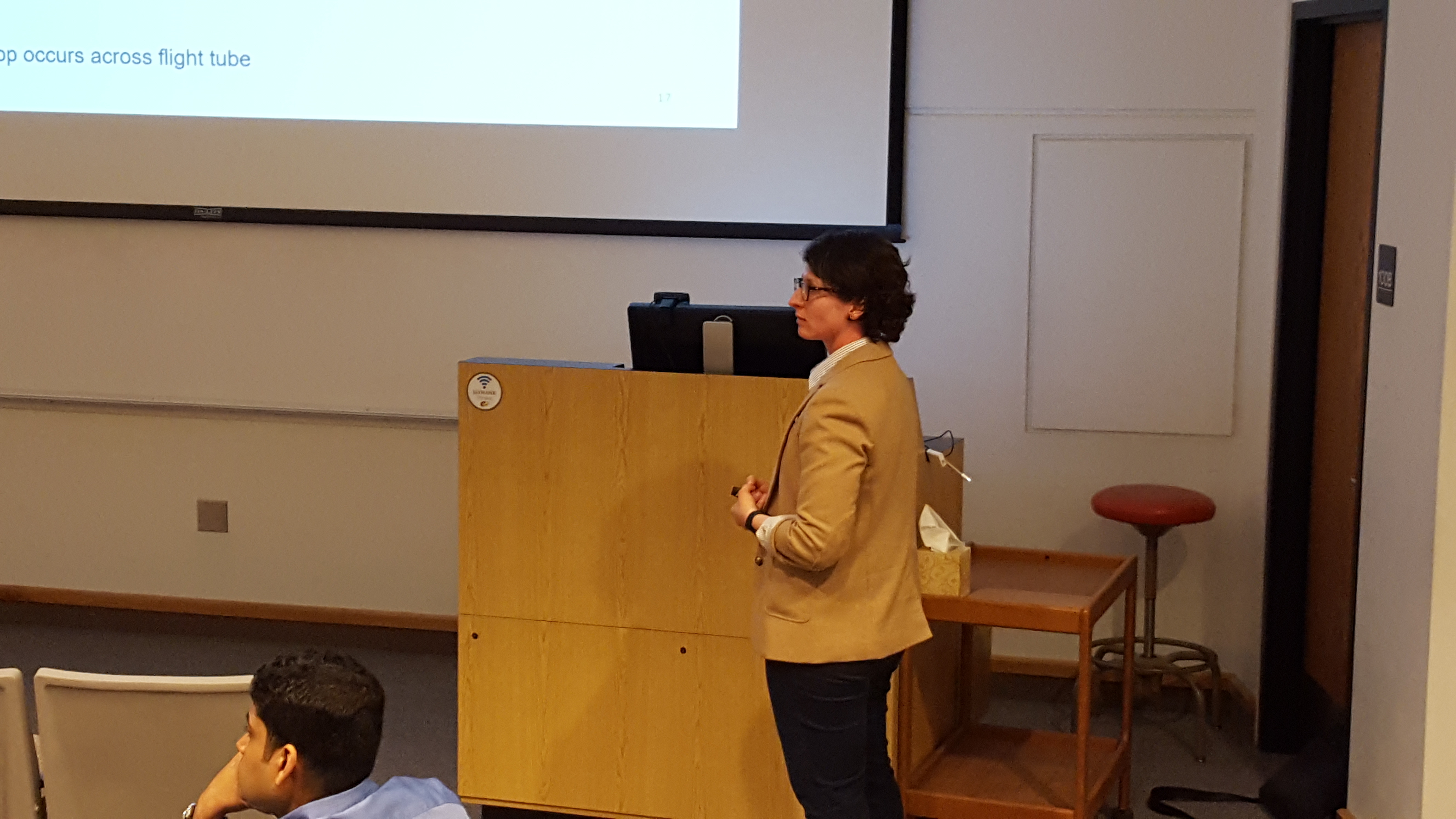 Orator delivering a presentation to a gathered audience in a spacious auditorium.