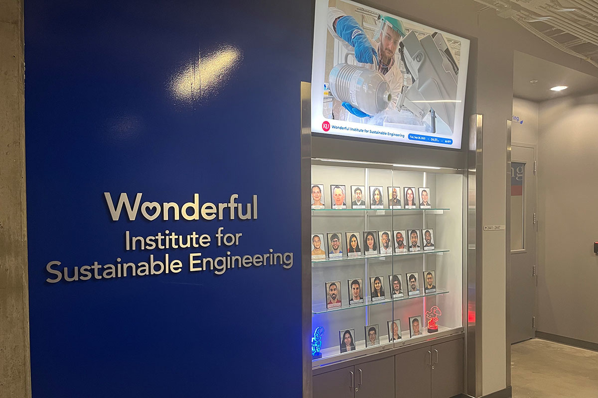 Signage for the Wonderful Institute for Sustainable Engineering-KU, white text on royal blue background, next to glass display case with portraits.