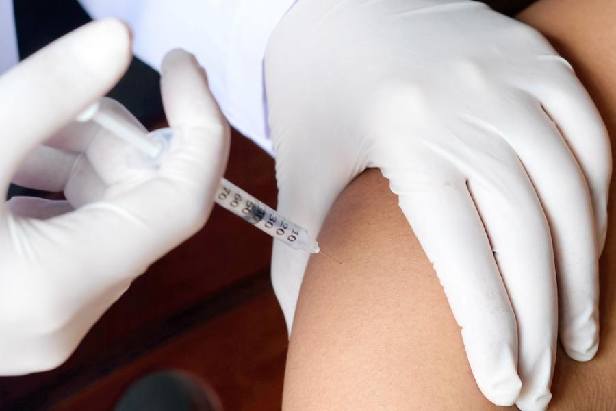 A doctor vaccinates the arm of a teen.