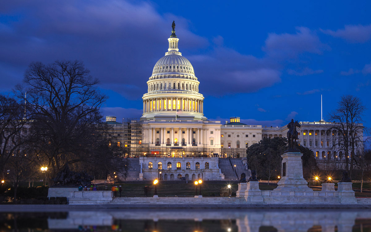 A photograph of the US Capitol, lit up at night.