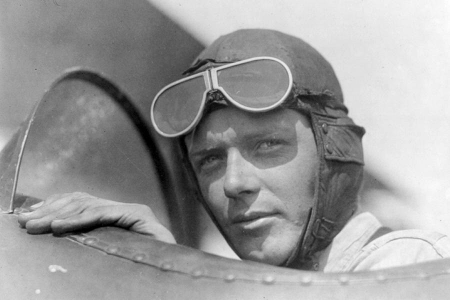Aviator Charles Lindbergh wears a helmet with goggle up while sitting in the open cockpit of an airplane at Lambert Field in St. Louis.