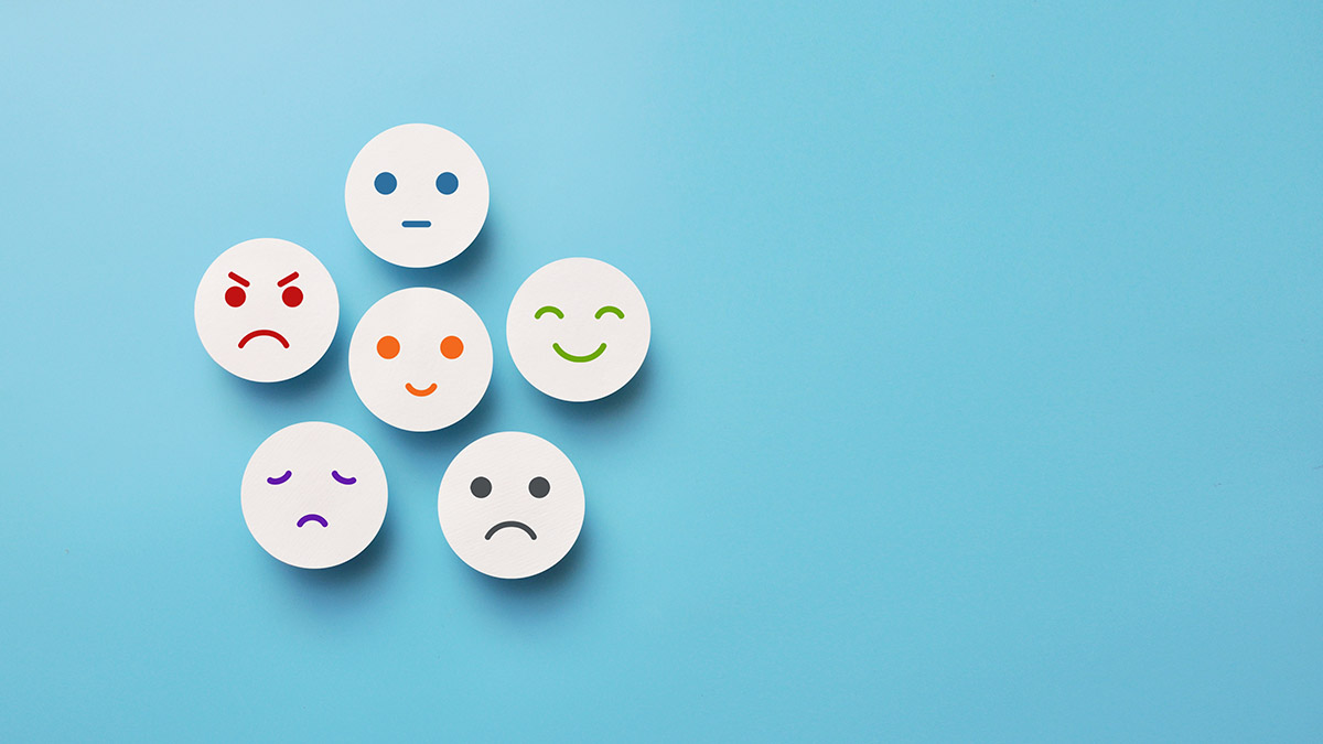 An illustration of several round buttons with drawn-on faces depicting a range of emotions such as happiness, sadness and frustration.