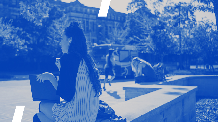 A woman sits on campus with a book open on her lap. This photo is color treated with blue tones.