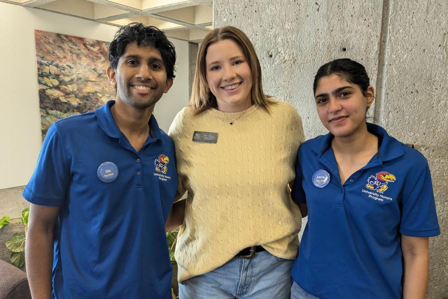 Two student ambassadors in blue polos pose for photo with staff member