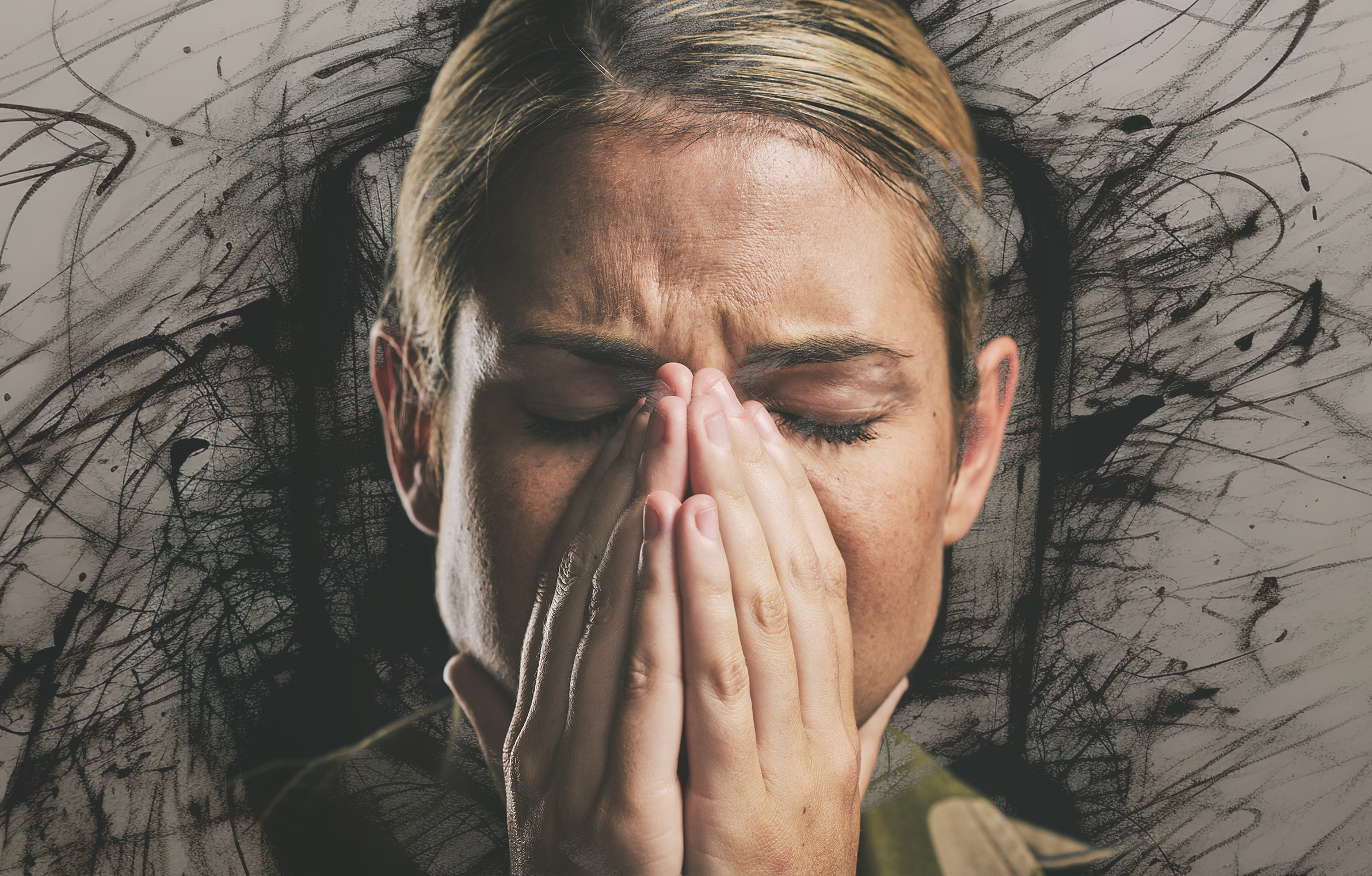 "A woman with a green uniform holds her hands over her face in an expression of distress"