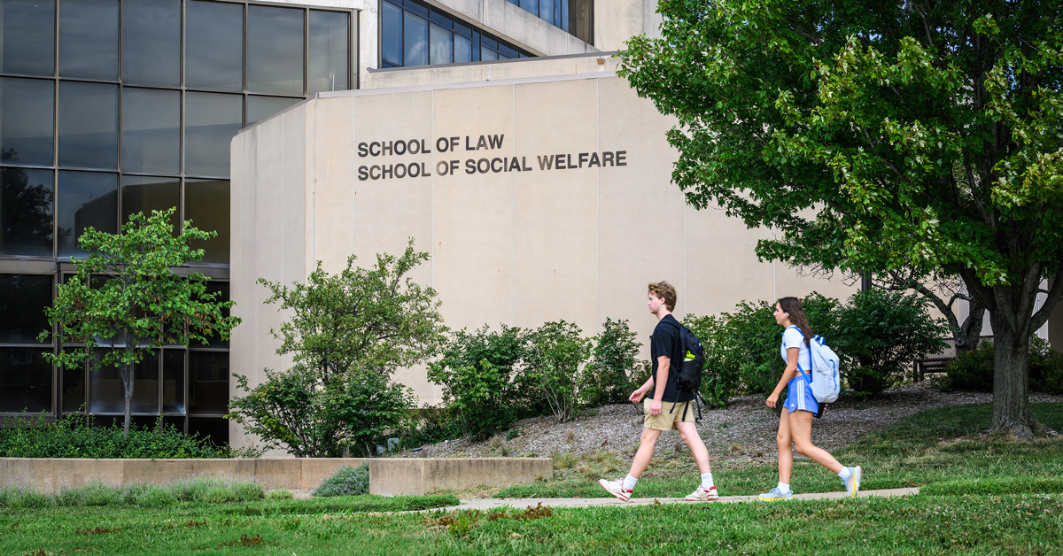 Students walk outside of Green Hall, home of the schools of social welfare and law, on the KU campus
