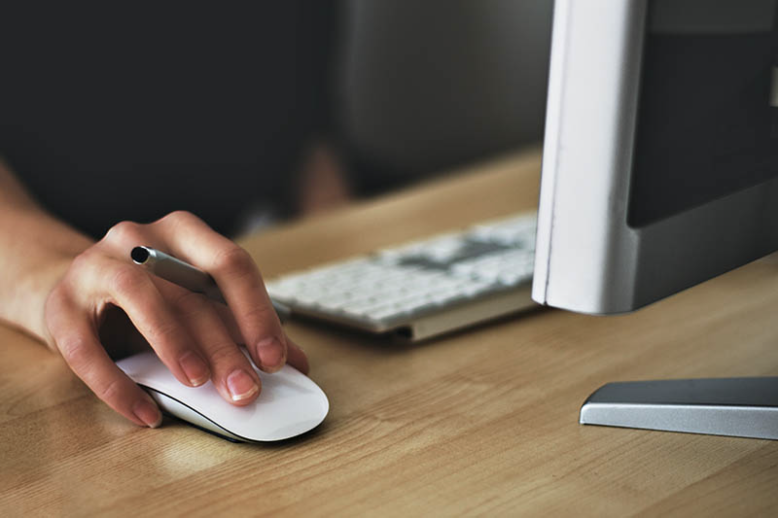 A person scrolls on a computer with a pen in hand