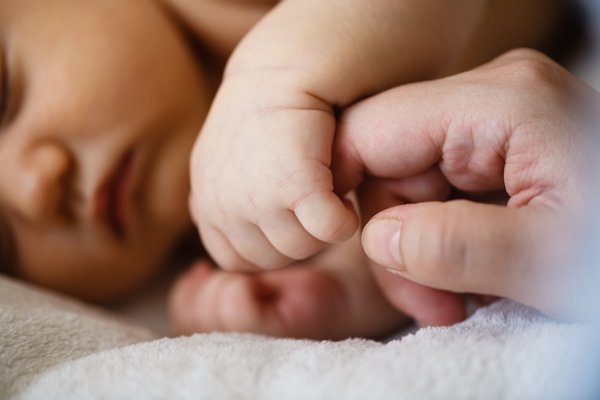 Infant holding hand of caregiver
