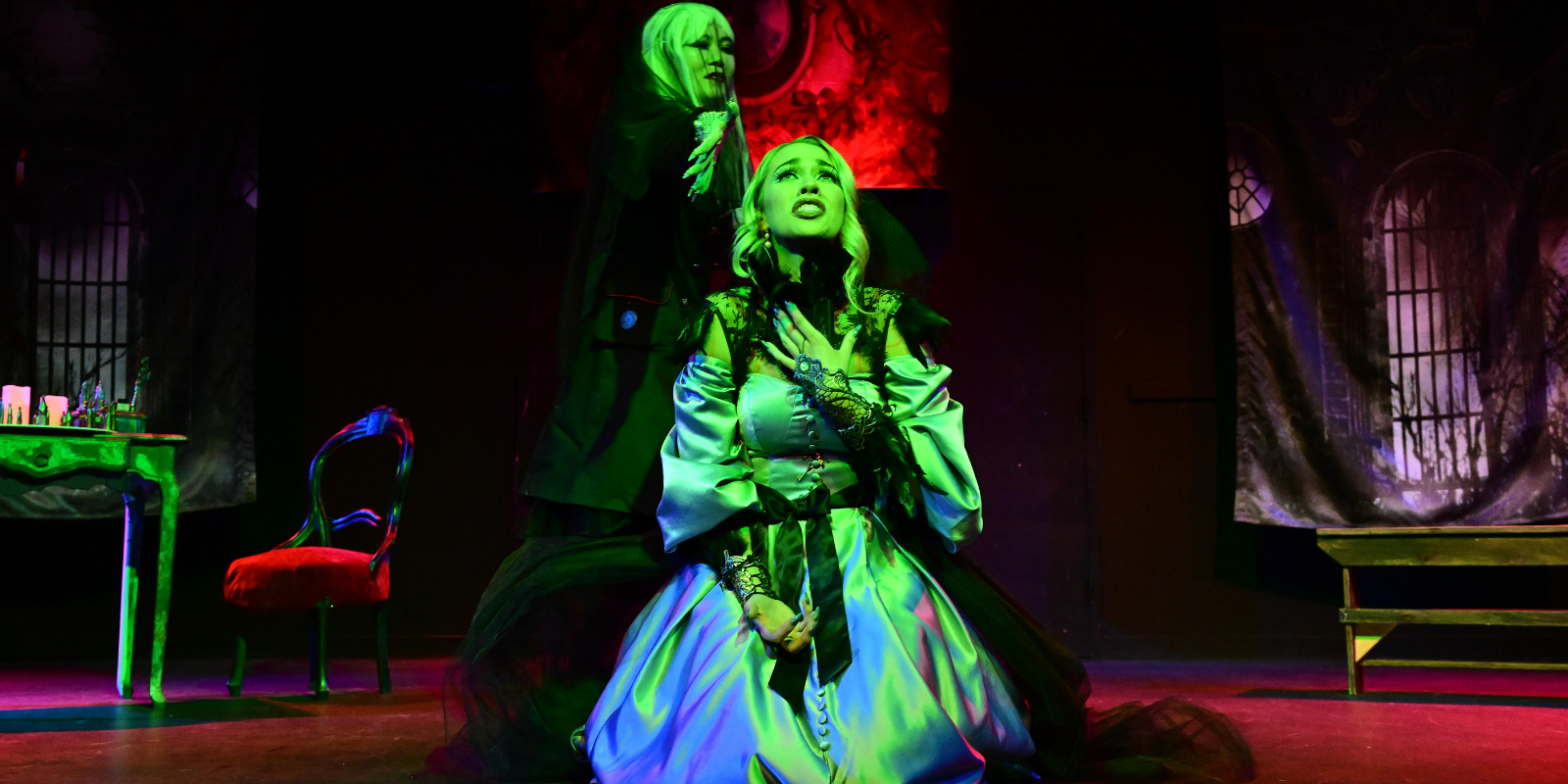 Two performers on a stage under green lighting.