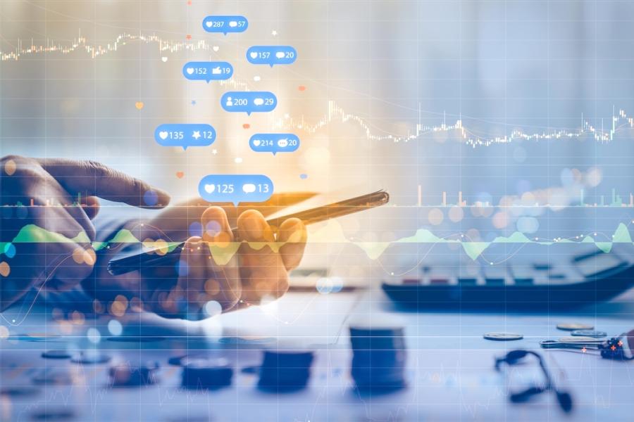 A hand holding a phone is shown liking posts on social media while a stock market graph is superimposed over the image.