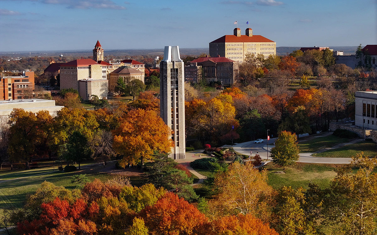 Aerial view of the University of Kansas Lawrence campus, Campanile in foreground surrounded by red and green fall foliage.