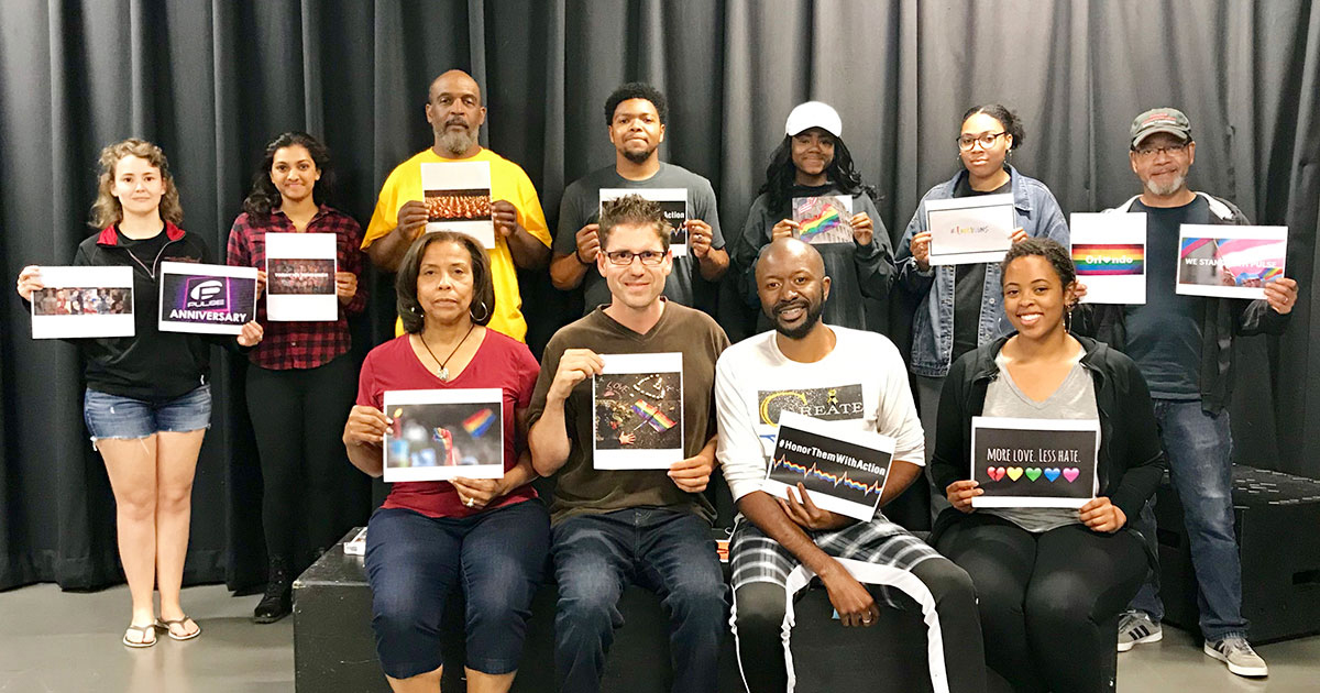 Paris Crayton III, Markus Potter and the cast and creative team of “Chasing Gods” hold signs memorializing the third anniversary of the Pulse nightclub shooting.