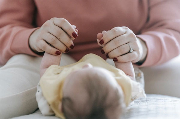 A mother holds a baby's hands