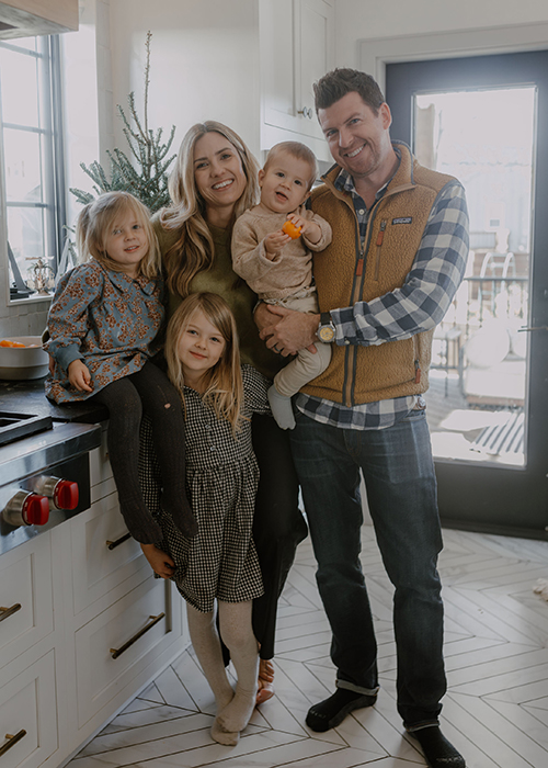A family of poses for a photo in a kitchen.