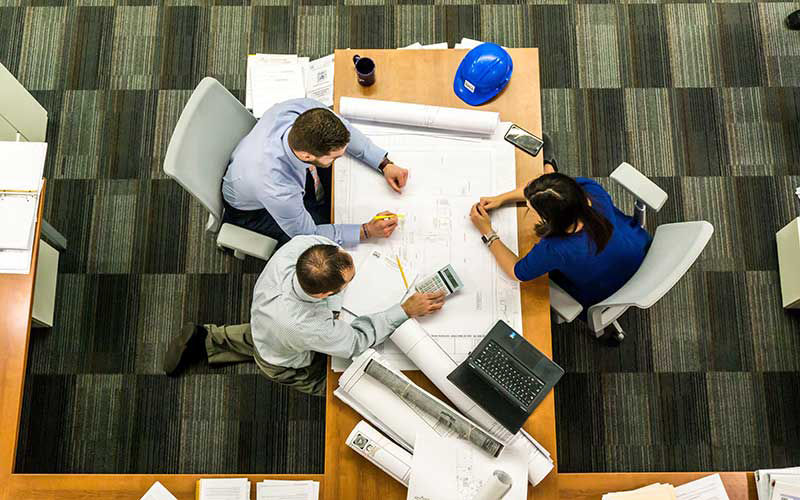 Colleagues gather around a table to discuss a project