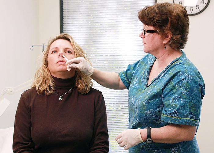 Stock image of woman receiving nasal vaccine.