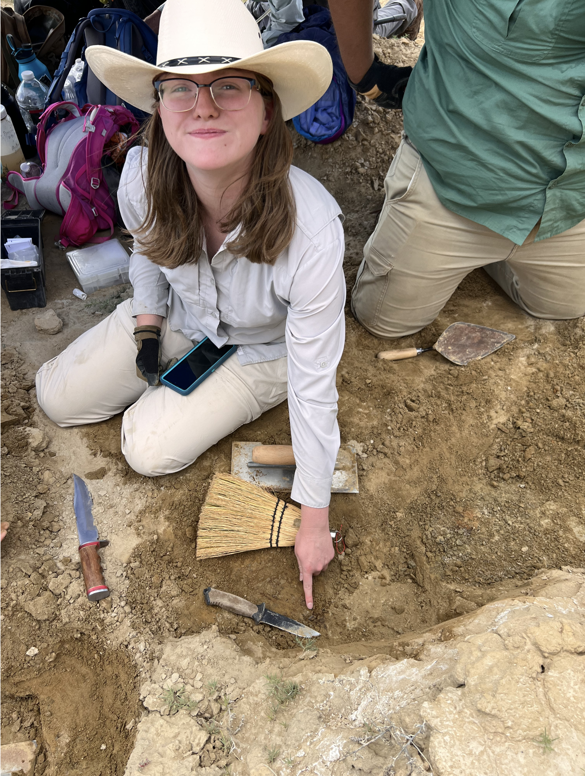 Sara Meyers, KU undergraduate student, points to a tyrannosaur tooth she found on the first day of the excavation. Credit: David Burnham